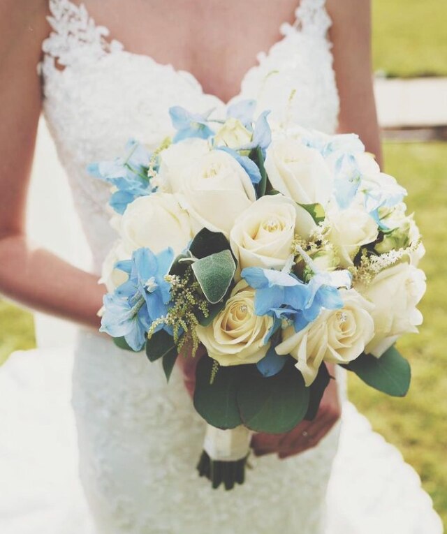 A beautiful bridal bouquet in blues and white being held by the bride